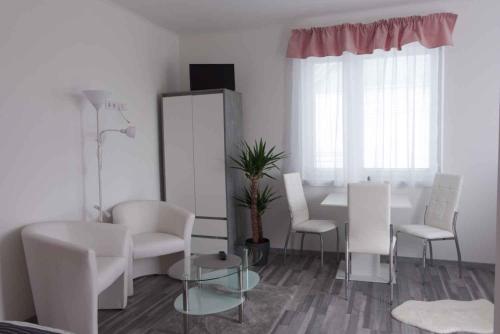 ein Wohnzimmer mit weißen Möbeln sowie einem Tisch und Stühlen in der Unterkunft Apartments in Bük - Nordtransdanubien 44085 in Bük