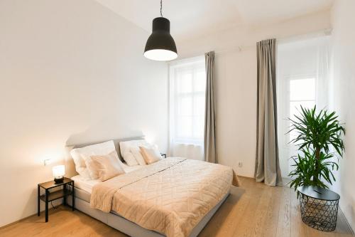 - une chambre blanche avec un lit et une plante en pot dans l'établissement Klimentská 52 Residence, à Prague