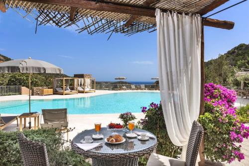 un patio con mesa y sillas junto a una piscina en Relais Villa Carola en Porto Cervo