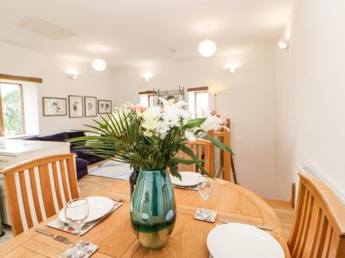 a dining room table with a vase of flowers on it at Whinstone in Keisley