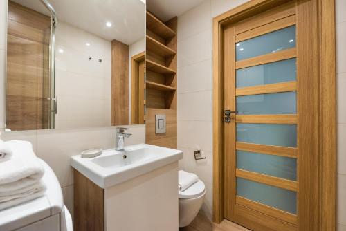 a bathroom with a sink and a toilet and a door at Mokotów Orzycka Beige Studio in Warsaw