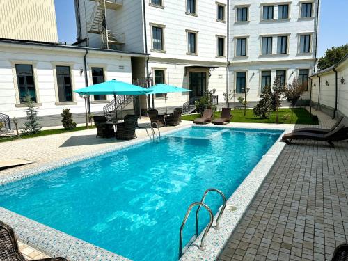 a large blue swimming pool in front of a building at Garnet Hotel Tashkent in Tashkent