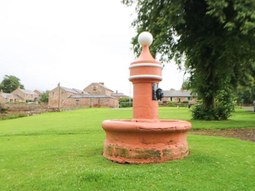 a brick tower in the middle of a field at Whinstone in Keisley