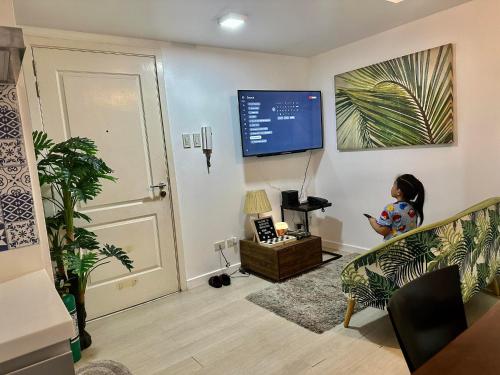 una sala de estar con TV y un niño sentado en un sofá en Pahuwayan1 - an Urban Tropical Retreat, en Manila