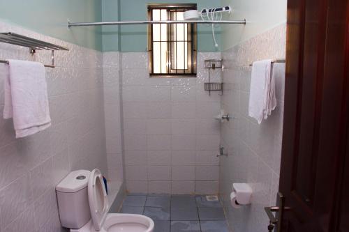 y baño blanco con aseo y ducha. en Lux Suites Greatwall Getaway Apartments, en Machakos
