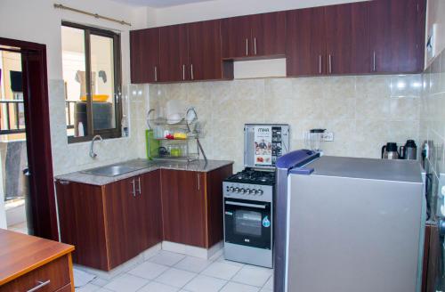 a kitchen with wooden cabinets and a white refrigerator at Greatwall Gardens Athiriver in Machakos