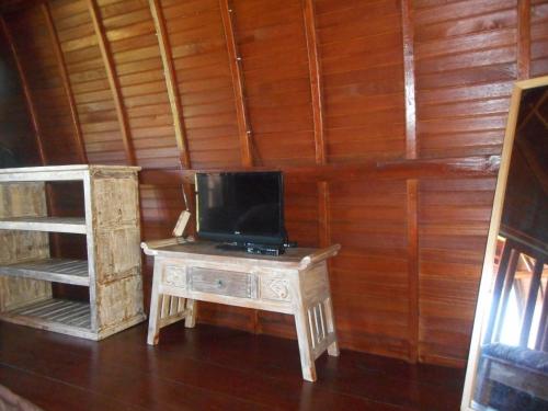 una TV seduta su un tavolo di legno in una stanza di Candra Homestay Besakih a Besakih