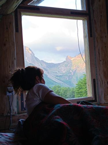 a woman laying on a bed looking out of a window at Komovi - Montenegrina Mountain house in Kolašin