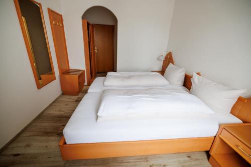 una camera con due letti con lenzuola bianche di Drexl Gasthof Shiro a Schondorf am Ammersee