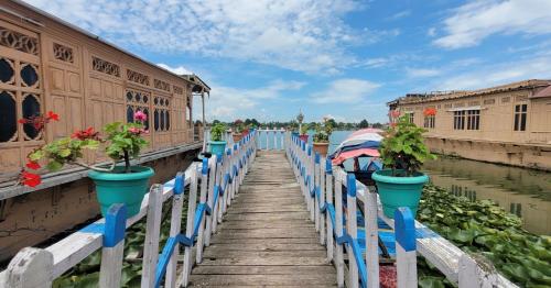 a wooden bridge with potted plants on it next to the water at Lily Of The World Houseboat in Srinagar