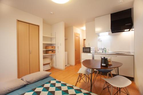 a bedroom with a bed and a table and a kitchen at Casa Matsubara in Tokyo