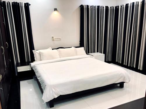 a bed in a room with black and white curtains at Garuda Suites in Varkala