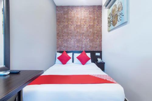 OYO 876 Hotel Sanctuary في بيتالينغ جايا: غرفة نوم عليها سرير ومخدات حمراء