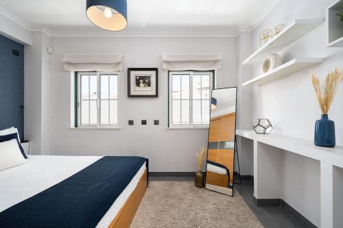 um quarto com uma cama e duas janelas em Downtown Pool House em Faro