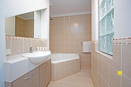 ein Badezimmer mit einem Waschbecken, einem Spiegel und einer Badewanne in der Unterkunft The Pearl in Jurien Bay