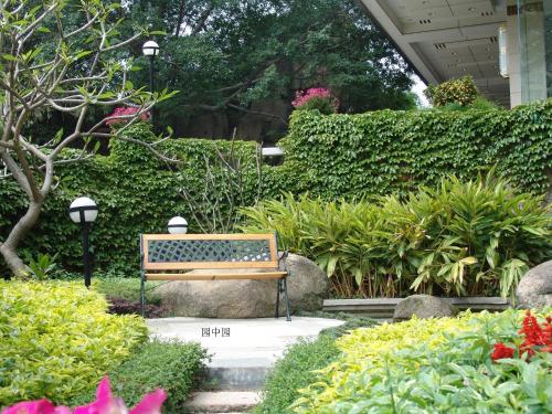 a bench in a garden with flowers and plants at City Hotel Xiamen-Free Welcome Fruits in Xiamen