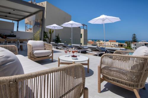 a patio with chairs and tables and umbrellas at Villa Manu Luxury Living in Stalos