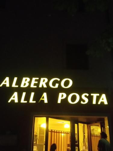 a sign that reads albergo alla piscina at night at Albergo Alla Posta in Anduins