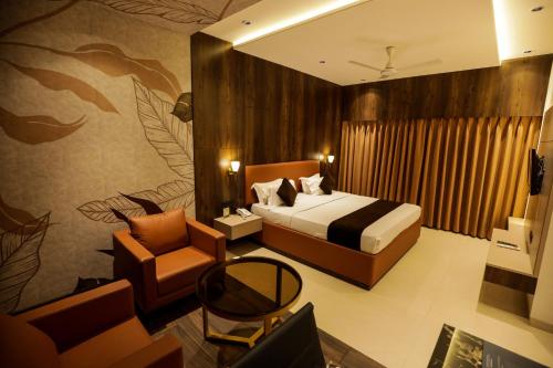a hotel room with a bed and a chair at Hotel Atithi, Aurangabad in Aurangabad