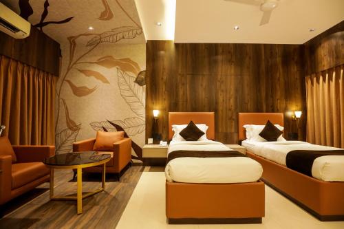 a hotel room with two beds and a couch at Hotel Atithi, Aurangabad in Aurangabad