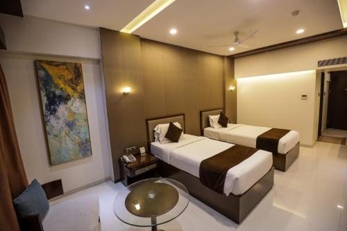 a hotel room with two beds and a table at Hotel Atithi, Aurangabad in Aurangabad