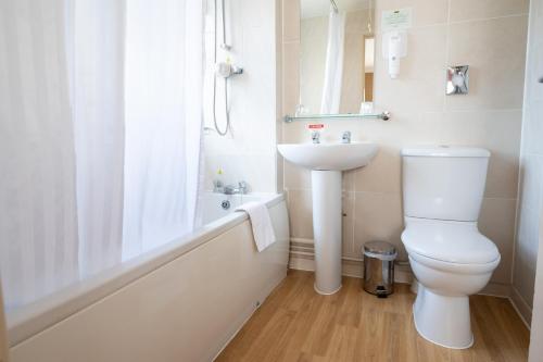 Baño blanco con aseo y lavamanos en Millers Hotel by Greene King Inns, en Sibson