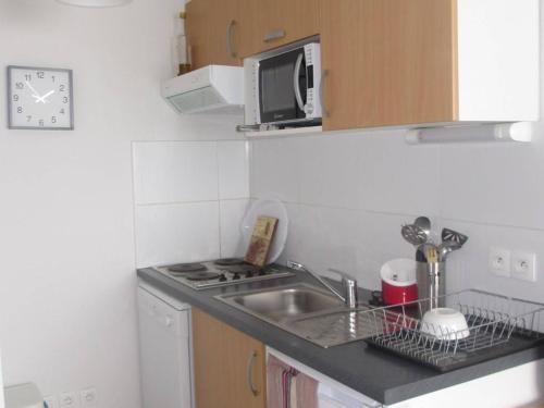 une petite cuisine avec un évier et un micro-ondes dans l'établissement Appartement cosy 6 pers. à Arette, 2 chambres, kitchenette, lave-vaisselle, lave-linge, casier à skis - FR-1-602-51, à Arette