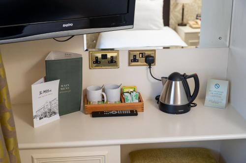 a desk with a tv and a tea kettle on it at Millers Hotel by Greene King Inns in Sibson