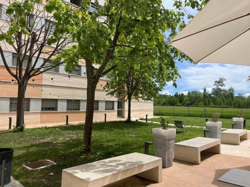 un gruppo di panchine e un ombrello di fronte a un edificio di Residencia Universitaria Los Abedules a Pamplona