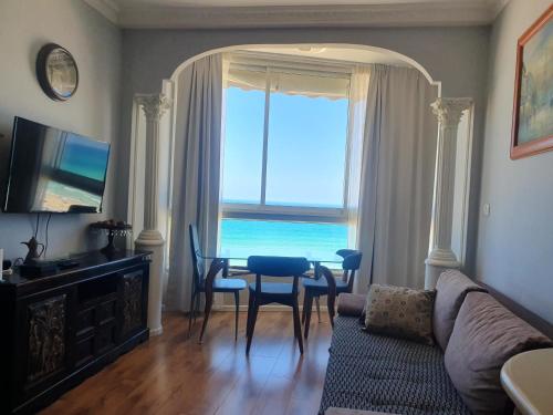 a living room with a couch and a table and a window at Sea View Deluxe in Bat Yam
