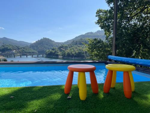 two colorful stools sitting next to a swimming pool at Estrela do Geres in Geres