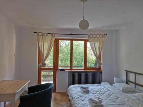 a bedroom with a bed and a table and a window at Evergreen Condo in Braşov