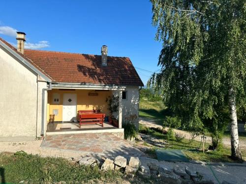 a small house with a red bench on a patio at Gazdinstvo Tadić in Nikšić