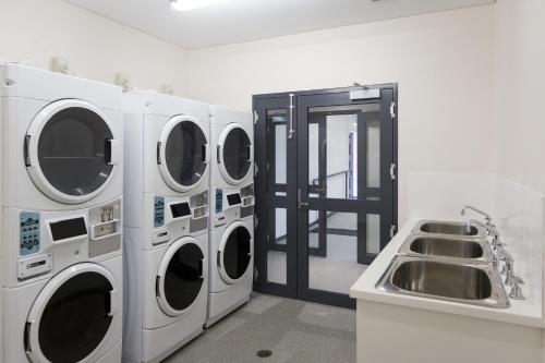 a laundry room with three washing machines and a sink at Fremantle Prison YHA in Fremantle