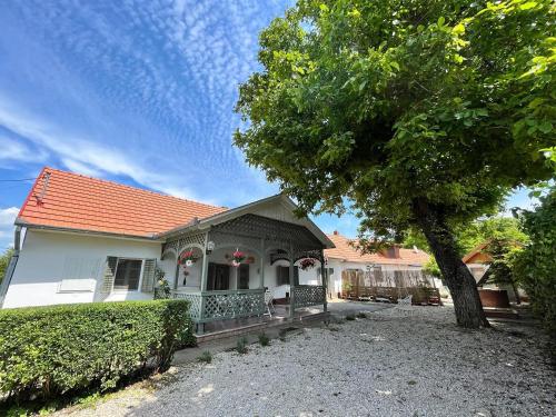 Una casa blanca con un árbol delante. en Veranda Porta, en Ordacsehi