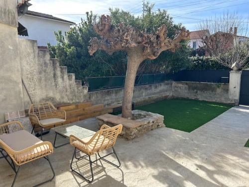 een patio met een boom, 2 stoelen en een tafel bij Villa proche centre Montpellier in Montpellier