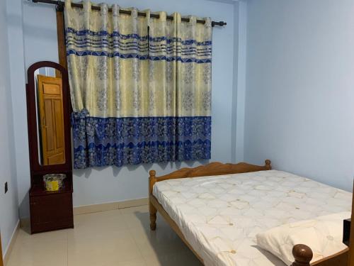 a bedroom with a bed and a curtain at Ahi House in Kilinochchi