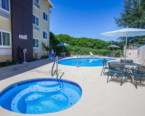 a pool with chairs and a table and an umbrella at Quality Inn Kirkland in Kirkland