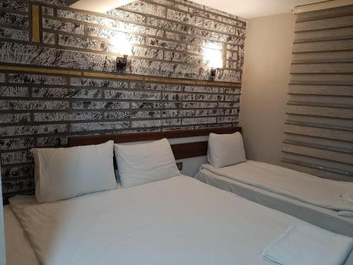 a bedroom with a bed and a brick wall at Hotel Kafkasya in Kars