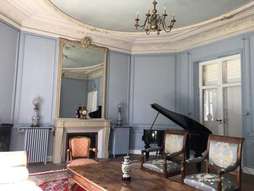 a living room with a piano and a mirror at Château de Maucouvent in Nevers