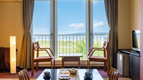 - un salon avec une table, des chaises et une grande fenêtre dans l'établissement Kagariya, à Abashiri