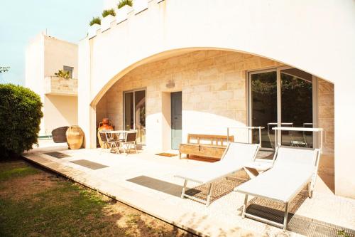 a patio with two white chairs and a table at Wp Relais apartments in Diso