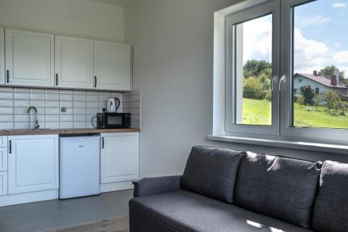 a living room with a couch and a kitchen with a window at Zajazd Tadeo in Pietrzykowice