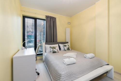 een slaapkamer met een bed met witte kussens en een raam bij Stary Browar Półwiejska Apartment with AC by Renters in Poznań