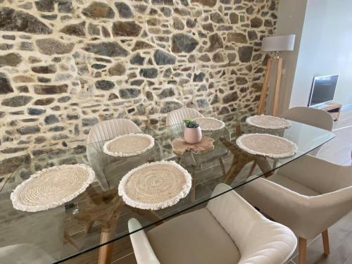 einen Glastisch mit Stühlen und eine Steinmauer in der Unterkunft Granville / Maison entièrement rénovée à 100 m des plages in Granville