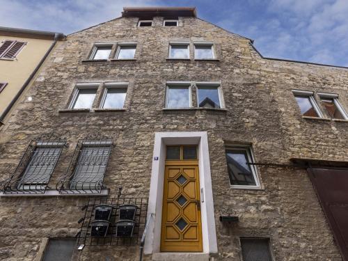 a brick building with a yellow door and windows at homie stay Badgasse - Fewos am Main mit Dachterrasse & Fahrradgarage in Ochsenfurt