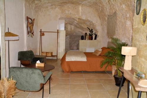 a bedroom with a bed and a chair and a table at Les Troglos de la Tufolière in Rochecorbon