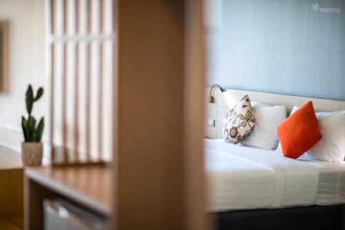 a bed with orange and white pillows in a room at Phavina Grand Boutique in Rayong