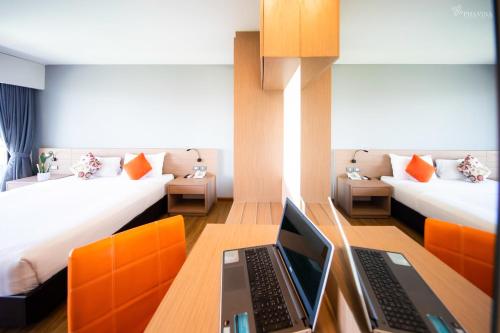 a room with two beds and a laptop on a desk at Phavina Grand Boutique in Rayong