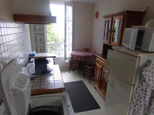 une petite cuisine avec un réfrigérateur et une table dans l'établissement Pres des thermes, à Bagnères-de-Bigorre